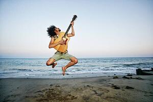 Art Photography Mixed Race man playing guitar and jumping at beach, Peathegee Inc, (40 x 26.7 cm)